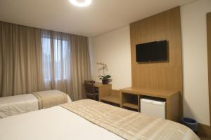 a hotel room with two beds and a flat screen tv at Casablanca Center Hotel in Petrópolis