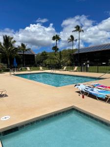 una piscina con mesa, sillas y palmeras en Ka Hale Kealoha, en Kaunakakai