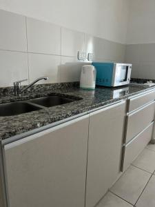 a kitchen counter with a sink and a microwave at Multi home in Concepción del Uruguay +14 photos