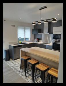 una cocina con una encimera grande con taburetes. en COSY HOME - Wifi - Paris/Orly - Accès 24/24 en Sainte-Geneviève-des-Bois