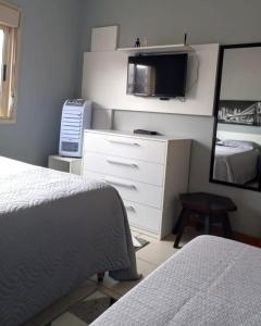 a bedroom with a bed and a dresser and a mirror at Apto POTY- 4 Pessoas - Ótima localização - 150 m do mar in Capão da Canoa