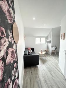 a living room with a black couch and flowers on the wall at Appartement cosy & reposant in Beauvais