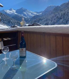 a bottle of wine sitting on a glass table with two wine glasses at Chalet Olympie, Appartement avec balcon et vue montagne, ski aux pieds, Méribel-Mottaret in Méribel