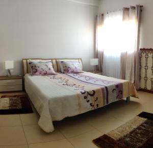 Un dormitorio con una cama con almohadas rosas y una ventana en Prothea Home en Vila Chã