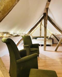 a room with two chairs and a bed in a attic at Chateau d'Humieres holiday cottage in Humières
