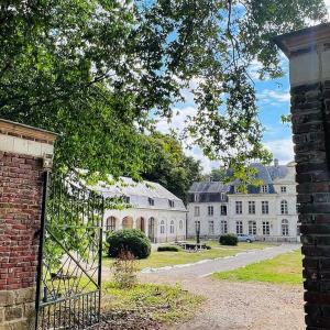 Chateau d'Humieres holiday cottage في Humières: مبنى ابيض كبير امامه بوابة