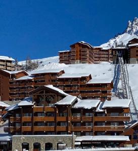 un hôtel dans la neige avec des toits recouverts de neige dans l'établissement Chalet Olympie, Appartement avec balcon et vue montagne, ski aux pieds, Méribel-Mottaret, à Méribel