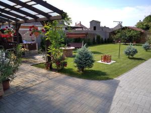 einen Hinterhof mit einem Garten mit Bäumen und einer Pergola in der Unterkunft Mözsi Apartman Tolna in Tolna