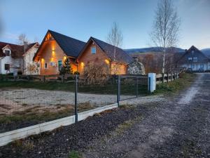 a house with a fence in front of a dirt road at Słoneczna Osada Domki w górach na wyłączność in Kowary