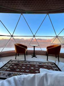 a room with two chairs and a table and a large window at Amanda Luxury Camp in Wadi Rum