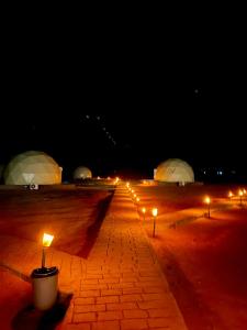 Amanda Luxury Camp في وادي رم: صف من الأضواء على طريق من الطوب في الليل