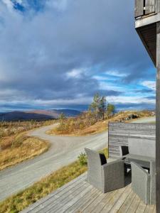 a deck with two chairs and a table and a road at Målselv Fjellandsby selveierleilighet in Bergset