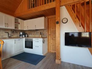 a kitchen with white cabinets and a tv on the wall at Holiday house at the Useriner See, Userin in Userin
