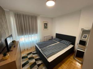 a bedroom with a bed and a mirror and a television at Korzo Osijek 2 in Osijek