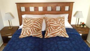 a bed with brown and white pillows on it at Departamento San Rafael - Sobre Paseo Chile in San Rafael