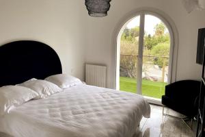 sypialnia z łóżkiem i dużym oknem w obiekcie VILLA LA QUIETUDE w mieście Les Issambres
