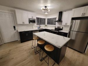 a kitchen with white cabinets and a large island with stools at The NW Olympic Retreat in Port Angeles