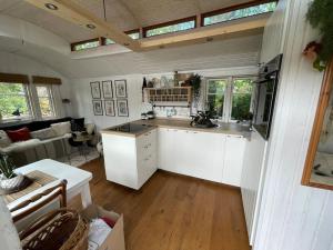 a kitchen with white cabinets and a living room at Tiny House Ostsee # Naturwerk in Pruchten