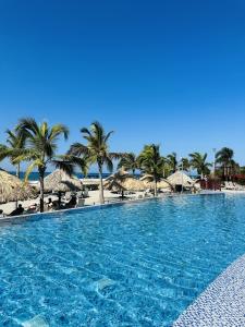 a large swimming pool next to a beach with umbrellas at Adela Suite in Santa Marta