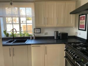 cocina con armarios blancos, fregadero y fogones en Cottage Number 5 in Southwold - Charming cottage gardens, en Southwold