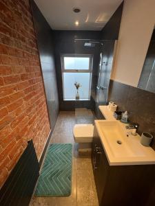 uma casa de banho com um lavatório e uma parede de tijolos. em Alsager Town Centre Apartment em Alsager