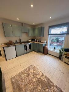 a large kitchen with green cabinets and a large window at Alsager Town Centre Apartment in Alsager