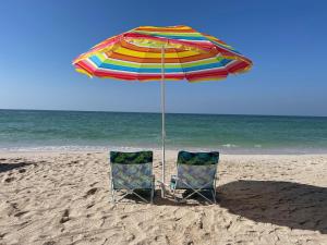 - 2 chaises sous un parasol sur la plage dans l'établissement Beachfront paradise just minutes from Dubai, à Ajman
