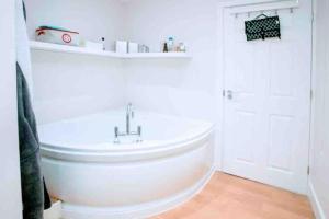 een badkamer met een wit bad en een wastafel bij Gold Penthouse - Near Basingstoke hospital 2min in Sherborne Saint John
