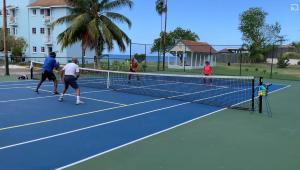 a group of people playing tennis on a tennis court at Point Village in Negril