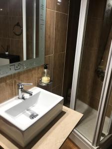 La salle de bains est pourvue d'un lavabo blanc et d'une douche. dans l'établissement Vivienda con fines turísticos ALMA, à Andújar