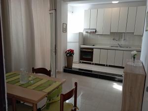 una cocina con armarios blancos y una mesa con sillas. en Apartmani Trubi en Vodice