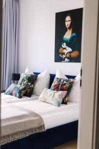 a bed with pillows and a painting of a woman at Design Apartman - Free parking in Szeged