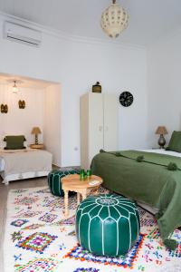 - un salon avec 2 lits verts et une table dans l'établissement Riad Dar Blanche & Spa, à Marrakech