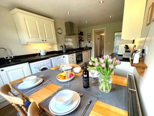 eine Küche mit einem Tisch mit Tellern und Blumen darauf in der Unterkunft Mulberry Cottage with Wood Burner, Garden and Easy Parking in Haworth