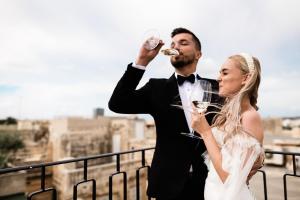 a bride and groom drinking wine from wine glasses at Palazzo Bifora Mdina in Mdina