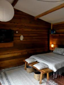 Bett in einem Zimmer mit Holzwänden in der Unterkunft Reserva Jacarandá Cabanas in Aiuruoca