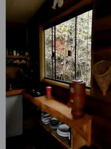 ein Fenster in einer Küche mit einem Tisch und Tellern in der Unterkunft Reserva Jacarandá Cabanas in Aiuruoca