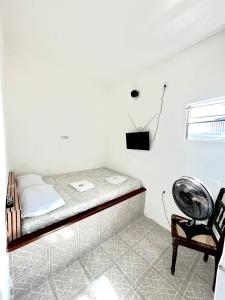 Ce lit se trouve dans un dortoir doté d'un ventilateur et d'une chaise. dans l'établissement Pousada Realce, à Vera Cruz de Itaparica