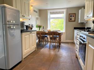 a kitchen with a table and a refrigerator at Mulberry Cottage in Haworth