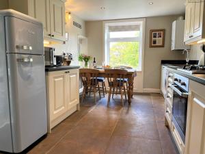 a kitchen with a table and a refrigerator at Mulberry Cottage with Wood Burner, Garden and Easy Parking in Haworth