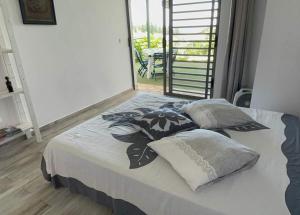 1 dormitorio con cama con almohadas y ventana en Tahiti RevaMiti EcoLodge, en Punaauia