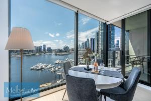 a dining room with a view of the water and boats at Melbourne Private Apartments - Collins Wharf Waterfront, Docklands in Melbourne