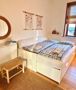a white bed in a room with a stool at En hel lejlighed i midtbyen - centralt, hyggelig og tæt på alt! in Randers