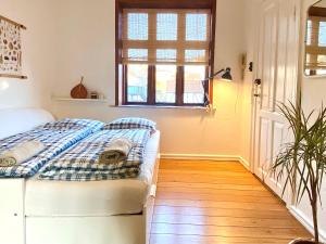 1 dormitorio con 1 cama con manta a cuadros y ventana en En hel lejlighed i midtbyen - centralt, hyggelig og tæt på alt!, en Randers