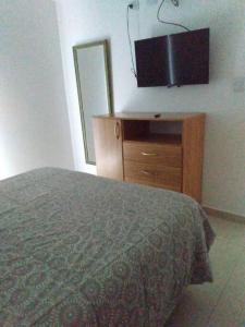 een slaapkamer met een bed en een dressoir met een flatscreen-tv bij Hermoso depto en excelente ubicacion in Puerto Madryn