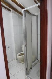 La salle de bains est pourvue de toilettes et d'une porte de douche en verre. dans l'établissement Hostal Turistico ILLAPA CUSCO 119, à Cusco