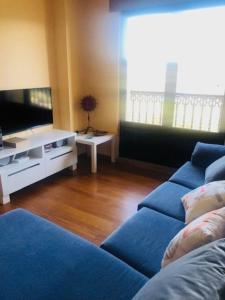 ein Wohnzimmer mit einem blauen Sofa und einem TV in der Unterkunft Piso moderno in Sarria