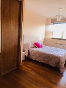 ein Schlafzimmer mit einem Bett mit einem rosa Kissen darauf in der Unterkunft Piso moderno in Sarria
