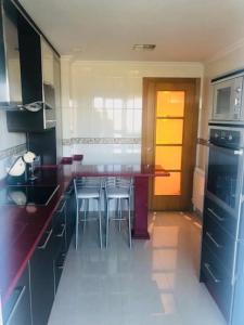 a kitchen with a counter with chairs and a table at Piso moderno in Sarria