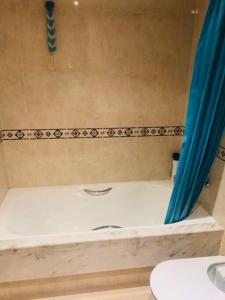 a bath tub with a blue shower curtain in a bathroom at Piso moderno in Sarria +5 photos